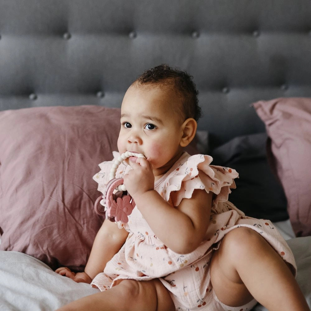 Baby sidder med Mushie bidering Fairy og bider i den – sikker og blød bidering til tandfrembrud